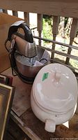 Hamilton Beach stand mixer and white ceramic serving bowl with lid placed on outdoor wooden surface