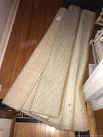 Rolled up wool rug laid on wooden floor, showing the full length and overall size