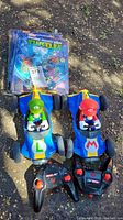 Two Mario Kart remote control cars featuring Luigi and Mario, along with their remotes included, placed next to the Teenage Mutant Ninja Turtles pop-up book.