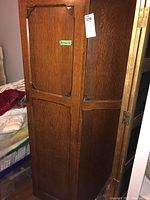 Full view of the wooden wardrobe showing its tall rectangular shape, wood grain, and carved panel details on door fronts. Tag with dimensions (36x40x72) is attached.