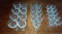 Top-down view showing 8 small wine glasses on the left, 9 sherry glasses in the middle, and 10 liqueur glasses on the right, each with clear cut crystal patterns.