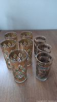 Overhead view of 8 decorative highball glasses arranged on table, showing two distinct styles and sizes