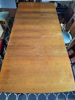 Top-down view of rectangular table top showing wood veneer surface with scratches and wear marks