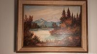 Frontal view of framed painting showing mountain landscape, lake, and autumn trees.