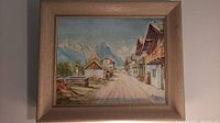 Oil painting showing village street with houses, mountains, and blue sky.
