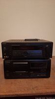 Sony STR-DE1075 amplifier stacked on top of Pioneer PD-F505 CD player on a wooden surface against plain wall.