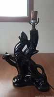 Side view of the vintage black glazed ceramic lamp showing the climbing puma on the tree trunk base with the socket on top.