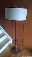 Full view of vintage teak standing lamp with fabric drum shade near stairs