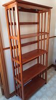 Full view of the wooden bookcase showing overall structure with vertical slatted sides and four shelves.