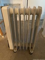 Photo of DeLonghi oil-filled radiator space heater showing side view with 7 fins and control panel area.