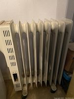 Side-angle photo of a white Honeywell oil-filled radiator heater with visible fins and control panel including a switch and dial, showing the heater's condition and design.