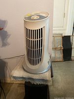 Front and side view of one Honeywell tower air purifier on a table displaying its vertical grill front and control knob on top.