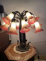 Lamp lit to show the 16 pink and white tulip lily-shaped glass shades on brass base.