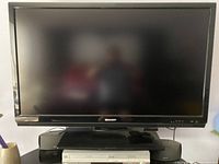 Photo of Sharp 46-inch LCD TV on stand with two black external speakers and a DVD/Blu-ray player underneath