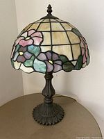 Front view of one Tiffany style stained glass table lamp with floral design and ornate metal base.