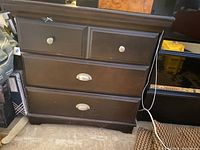 Front view of the wooden bedroom cabinet showing four drawers with metal knobs and handles, dark brown finish.