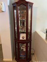 Full view of tall wooden cabinet with glass door and side panels, filled with crystal collectibles.