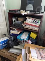 Wooden office bookcase with office items organized on shelves and on floor in front of it