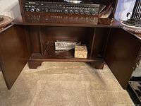 Open side cabinets showing interior storage space below audio control panel.