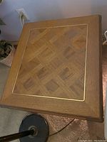 Top view photo showing square wooden side table with parquet patterned surface and inlaid border.