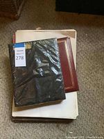 Stack of books and papers including one with a black protective cover.