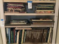 Full view of three shelves with stacks and rows of books highlighting subjects like weaving, gardening, and art.