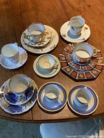 Assortment of nine china cups and saucers showing different patterns and styles