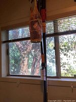 Fiskars tree trimmer and wicker basket hanging together by a window, showing handle and basket weave details.