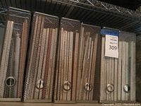 Ten silver metal mesh magazine holders arranged on shelf containing multiple magazines.