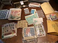 Overview of multiple stamp albums, loose pages, envelopes and stamp sheets spread on table