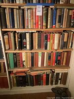 Bookshelf with four shelves filled with used books of various sizes and colors.