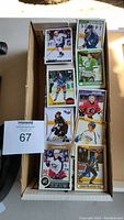 Photo of the box of assorted hockey cards with visible cards of various players in NHL uniforms featuring teams such as Calgary Flames, New York Rangers, and Buffalo Sabres.