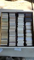 Full view of a box filled with stacks of assorted trading cards arranged in four columns.