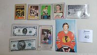 Five Bobby Orr hockey cards, two novelty bills, Boston Garden Orr Score photo, and 5x7 photo of Orr in Blackhawks uniform arranged on table