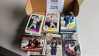 Box of mixed sports cards showing baseball and hockey cards on top