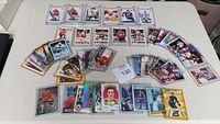 Wide shot of assorted hockey sports cards laid out on a white table, showing cards in different protective cases plus loose cards.