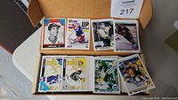 Box open showing stacks of hockey sports cards with players from various teams. Cards include images of players in action, rookies, and inserts.