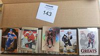 Several stacks of hockey cards featuring different players and logos from multiple teams and brands, displayed inside a box.