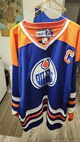 Front view of the Edmonton Oilers jersey showing team logo, captain patch, and color pattern.