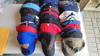 Photo showing rows of caps in various colors including black, blue, olive green, and red caps, some with logos and tags visible.