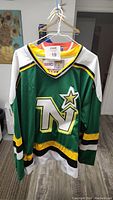 Front view of the vintage CCM North Star hockey jersey showing green color with yellow, black, and white stripes and large North Star logo with star and number 9 on front.