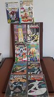 Ten copper age comic books arranged on chair including Marvel Age titles and ICG comic books.