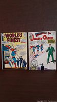 Front covers of two comic books: World's Finest Comics #148 and Superman's Pal Jimmy Olsen #63, displayed side by side on a dark surface.