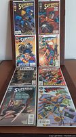 Photo showing all eight comic books in two rows, displaying the colorful covers featuring Superman in several poses and scenes.