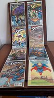 Eight DC Superman comic books arranged in two columns, showing vibrant covers featuring various Superman themes and characters, including The Adventures of Superman and Superman Action Comics.
