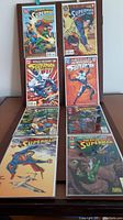 Eight Superman comic books arranged in two rows showing covers and spines. Covers feature colorful artwork with Superman in various dynamic action poses.