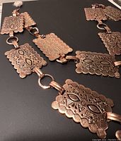 Close up of belt rectangular plates showing embossed patterns and scalloped edges