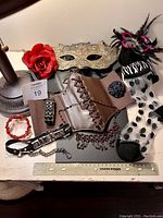 Photo showing assortment of costume accessories including mask, corset, stockings, belts, flower accessories, and jewelry, all on a white surface.