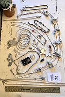 Full lot arranged on white surface showing multiple necklaces, bracelets, earrings, brooches, and bangles with measuring ruler for scale.