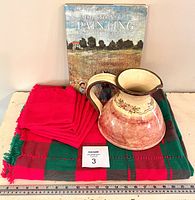 Overall set with pottery jug, book, tablecloth, and napkins arranged with measuring ruler.